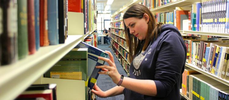 Image of a mature student choosing books from the shelves in the library